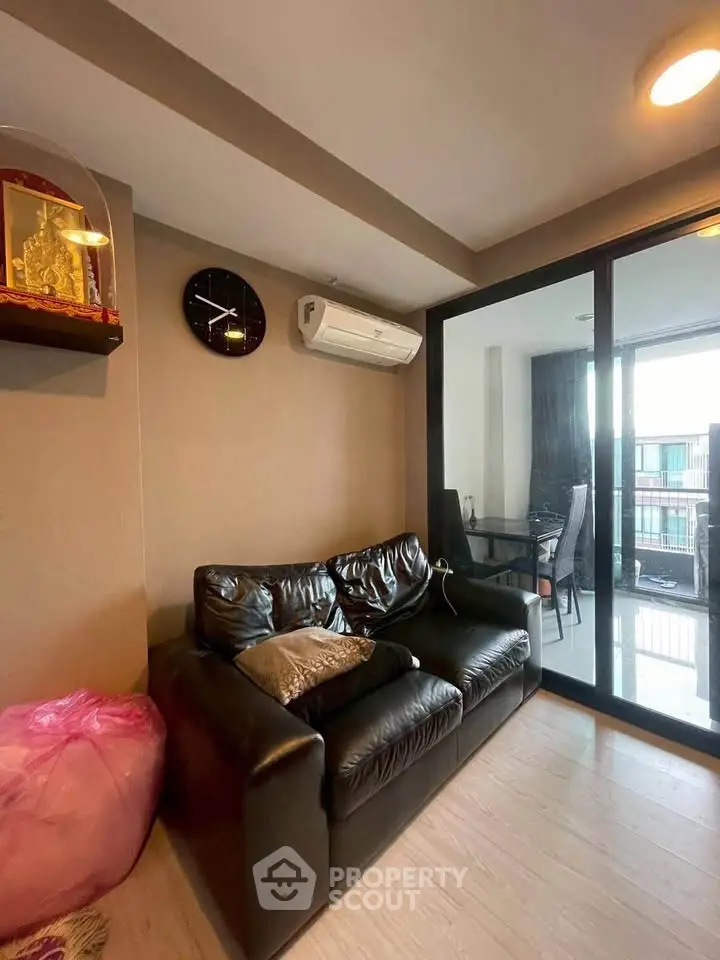 Modern living room with leather sofa and glass sliding doors leading to a balcony.