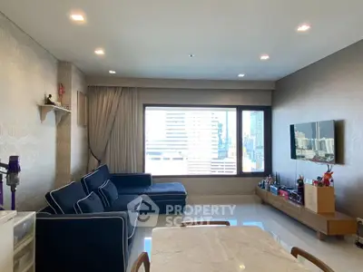 Spacious modern living room with large window and city view, featuring stylish furniture and elegant decor.