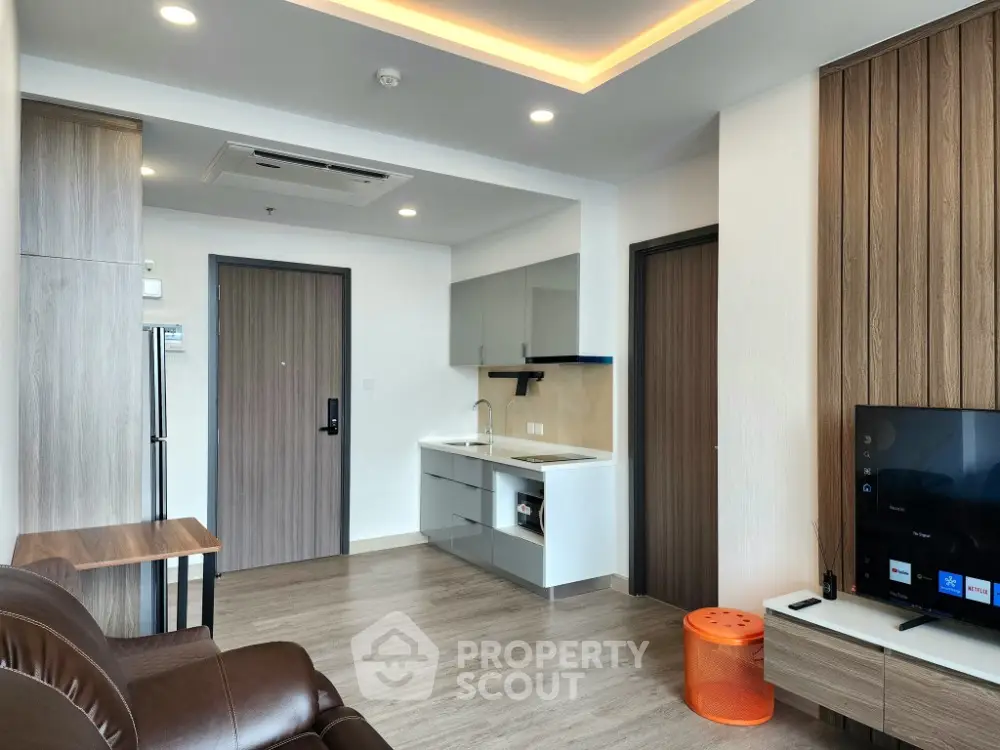 Modern living room with sleek kitchen and stylish decor in open layout apartment.