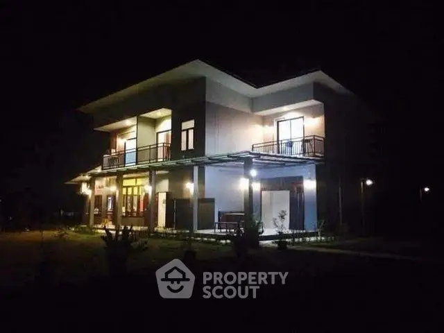 Stunning modern two-story house with illuminated exterior at night, featuring spacious balconies and sleek design.