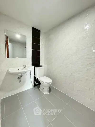 Modern minimalist bathroom with sleek white tiles and contemporary fixtures.