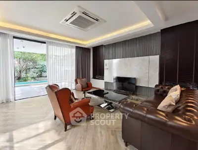 Luxurious living room with elegant leather furniture and pool view, perfect for relaxation and entertainment.