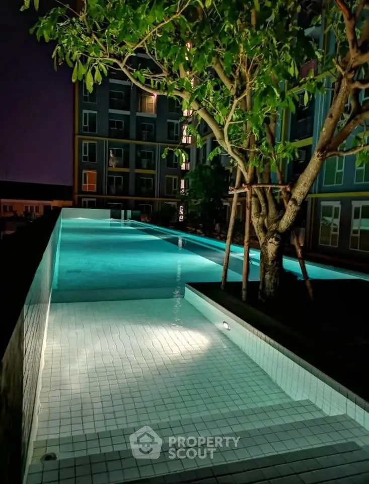 Luxurious night view of illuminated swimming pool with modern building backdrop.