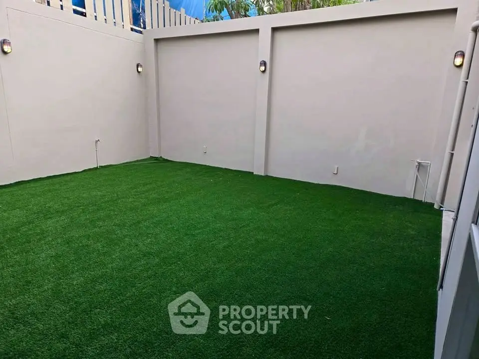 Spacious private garden area with lush green artificial turf and modern lighting, perfect for outdoor relaxation.