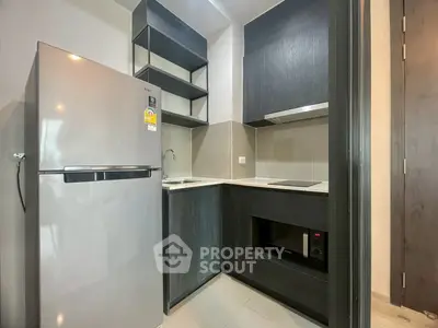 Modern compact kitchen with sleek cabinets and stainless steel fridge