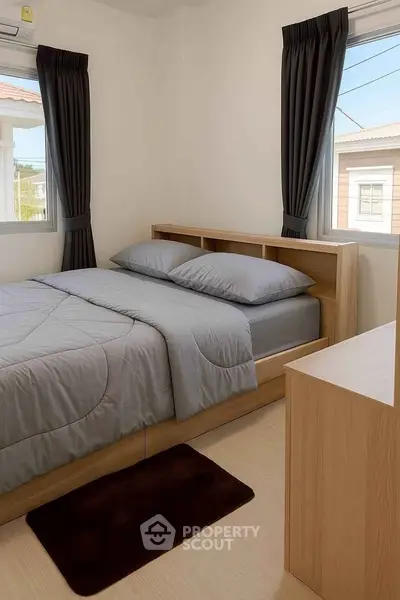 Cozy bedroom with modern wooden furniture and large windows for natural light.