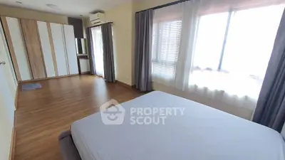 Spacious bedroom with large windows and wooden flooring in modern apartment