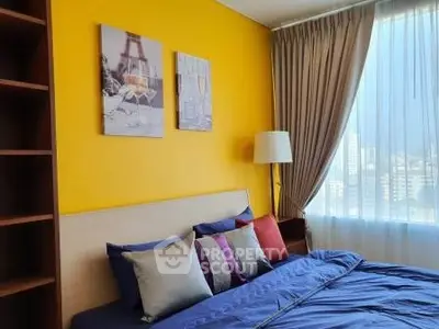 Bright bedroom with vibrant yellow accent wall and city view, featuring cozy bedding and elegant decor.