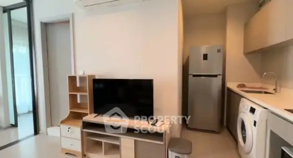 Modern apartment interior with TV, fridge, and washing machine in open layout.