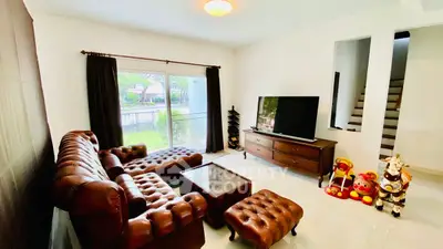 Charming living room with leather furniture and large TV, perfect for relaxation.