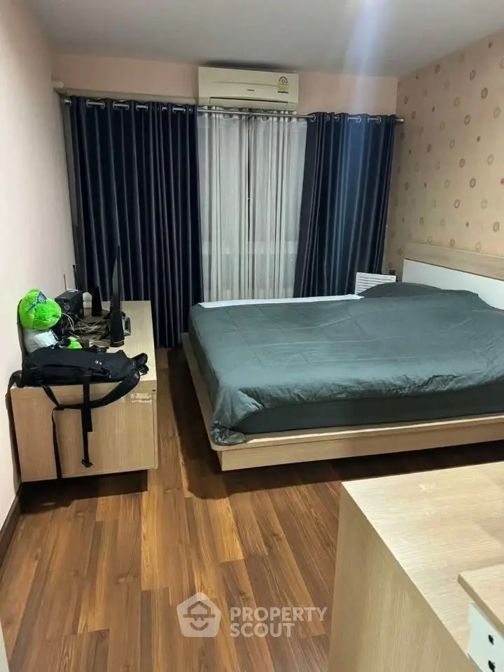 Cozy bedroom with wooden flooring and modern furnishings, featuring a comfortable bed and stylish curtains.