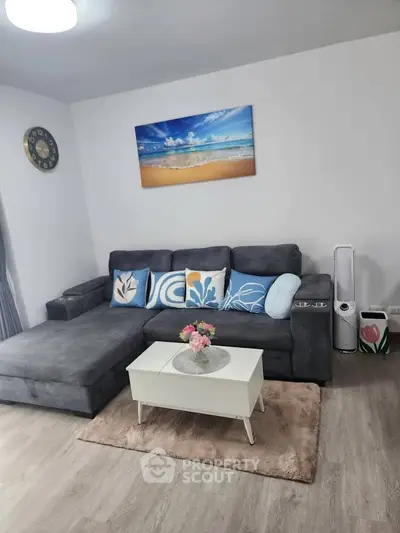 Stylish living room with modern gray sofa and beach artwork, perfect for relaxation.