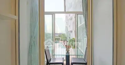 Charming balcony view with modern glass table and chairs, overlooking serene pool area in luxury apartment.