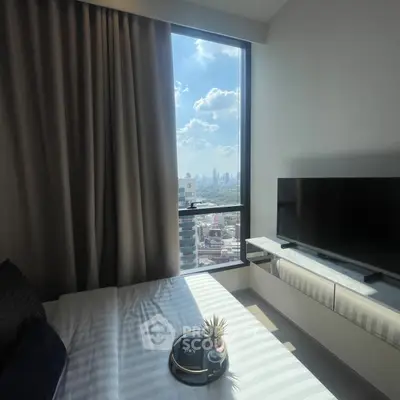 Modern bedroom with city view, featuring a large window and sleek TV setup.