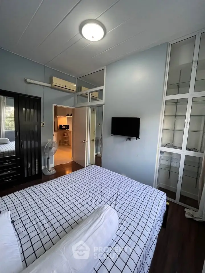 Cozy bedroom with modern decor, wall-mounted TV, and ample storage in a stylish apartment.