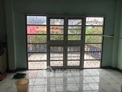 Spacious room with decorative metal doors leading to a balcony with a view.