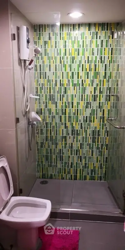 Modern bathroom with vibrant green mosaic tiles and glass shower enclosure.