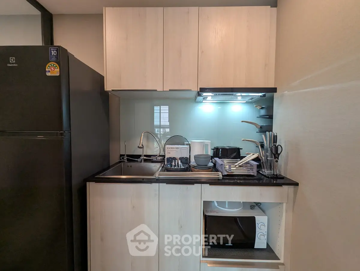 Modern compact kitchen with sleek cabinetry and appliances in a stylish apartment.