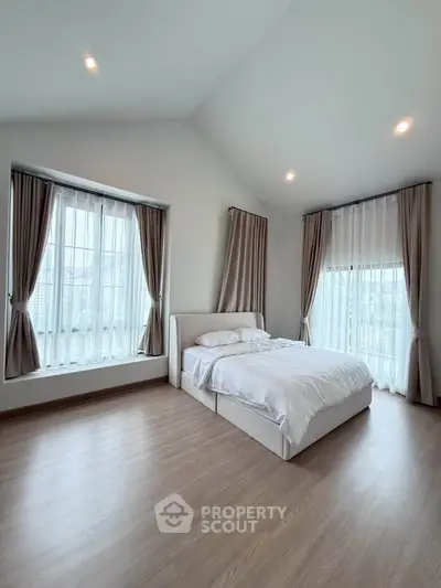 Spacious bedroom with large windows and elegant curtains in modern home
