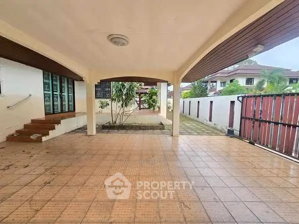 Spacious covered parking area with tiled flooring and garden view.