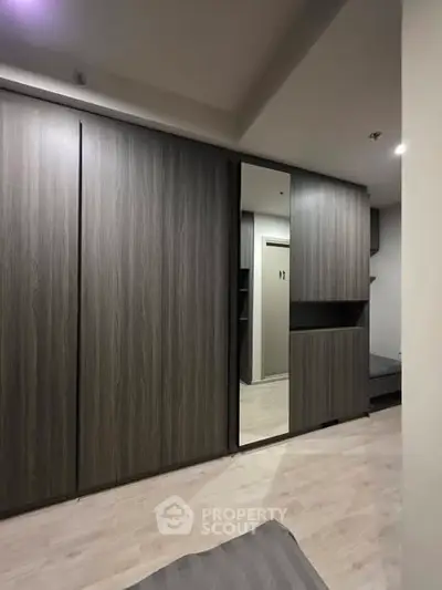 Modern bedroom with sleek built-in wardrobe and mirror, showcasing contemporary design and ample storage space.