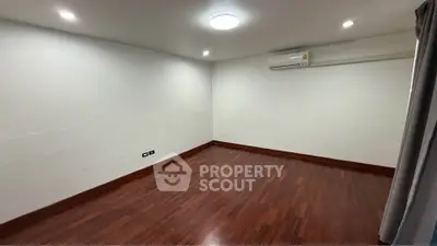 Spacious empty room with wooden flooring and air conditioning, ideal for customization.