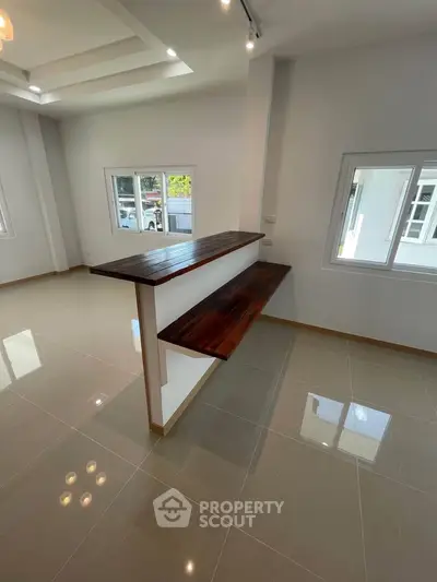 Modern open-plan living space with sleek tiled floors and wooden countertop