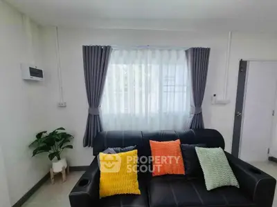 Modern living room with stylish sofa and colorful cushions, featuring elegant curtains and a potted plant.