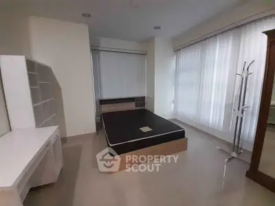 Spacious bedroom with modern furnishings and large windows for natural light.