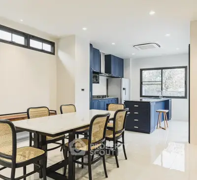 Modern kitchen with dining area featuring sleek design and natural light.