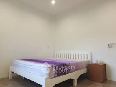 Cozy minimalist bedroom with white bed frame and purple bedding