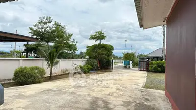 Spacious driveway with lush greenery and modern fencing in suburban setting.