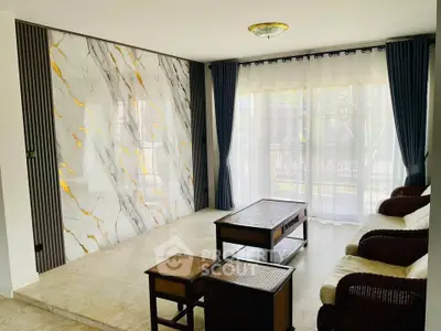 Elegant living room with marble accent wall and large windows, featuring stylish furniture and natural light.