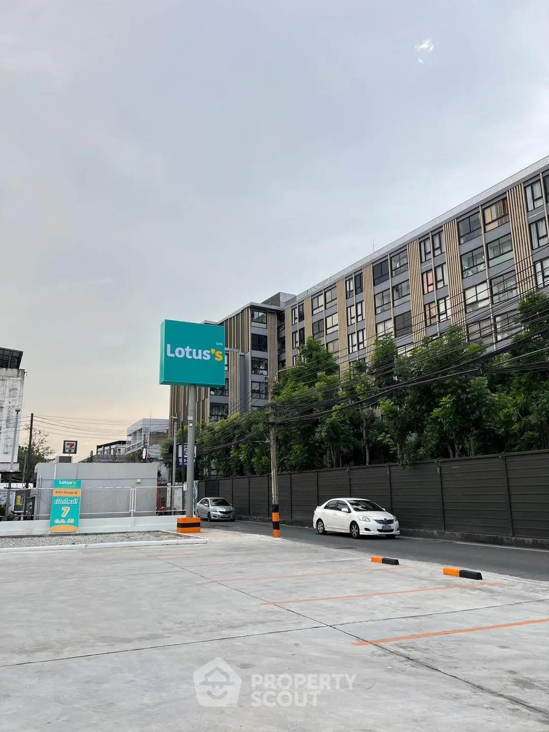 Modern apartment building with parking area and Lotus's sign in urban setting.