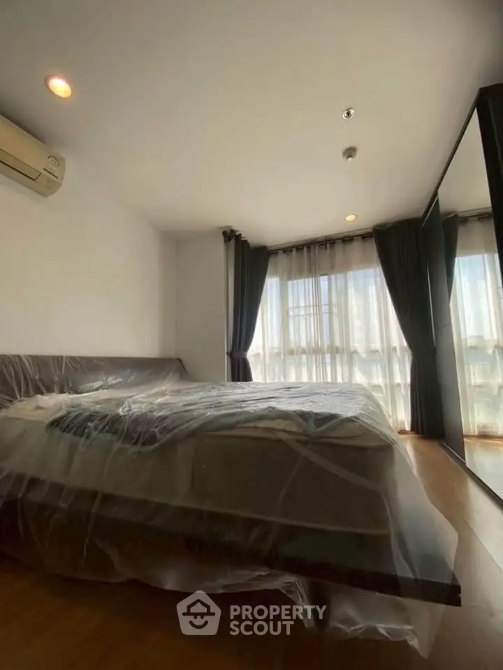 Spacious bedroom with large windows and modern furnishings, perfect for comfort and relaxation.