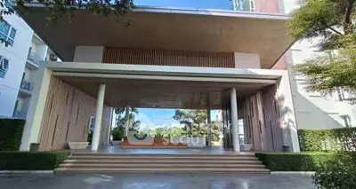 Modern building entrance with open-air design and lush greenery.