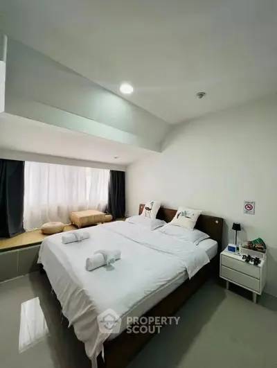 Modern bedroom with cozy bed and natural light, featuring sleek design and comfortable ambiance.