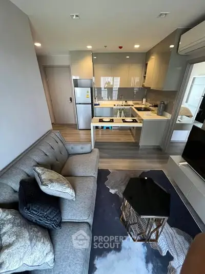 Modern living room with stylish kitchen, featuring sleek appliances and cozy seating area.