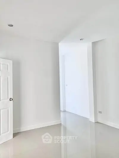 Spacious empty room with glossy tiled floors and white walls, perfect for customization.