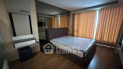 Modern bedroom with mirrored wall and large windows, featuring a stylish bed and wooden flooring.