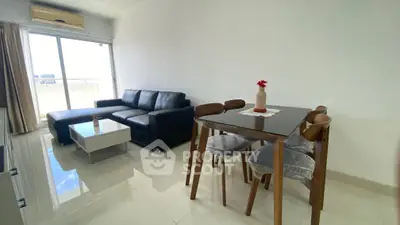Modern living room with sleek black sofa and dining set, bright natural light from balcony.