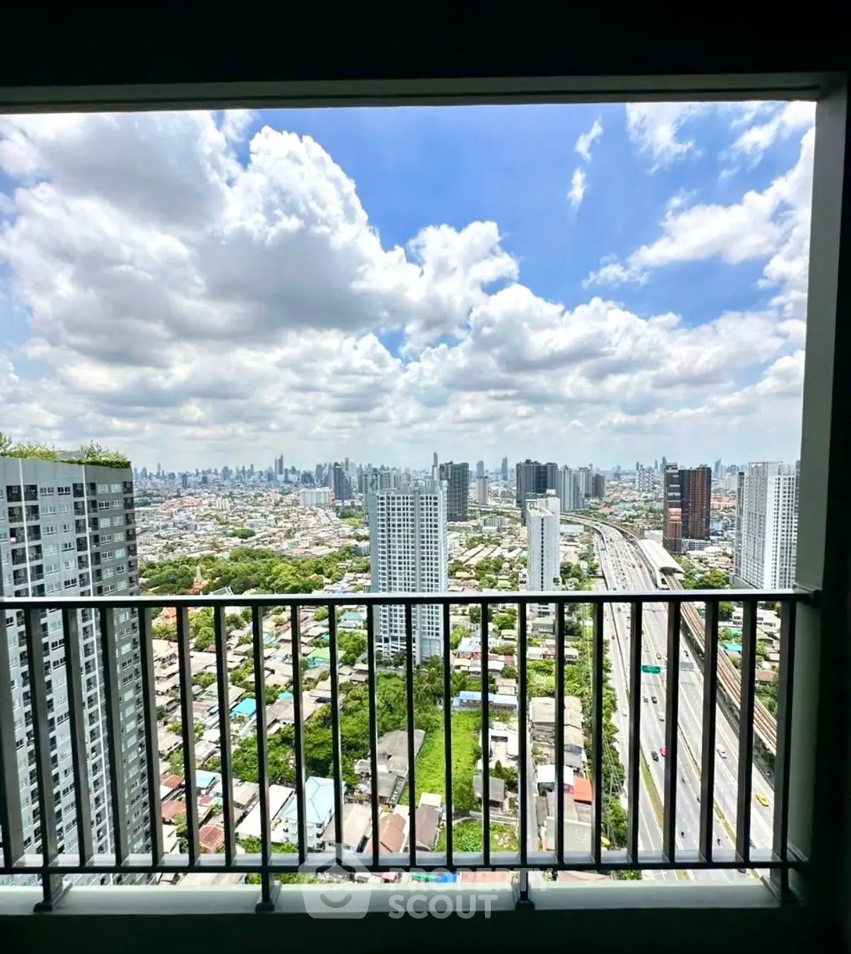 Stunning cityscape view from high-rise balcony with expansive skyline and lush greenery.