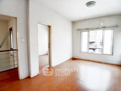 Spacious empty room with wooden flooring and large window