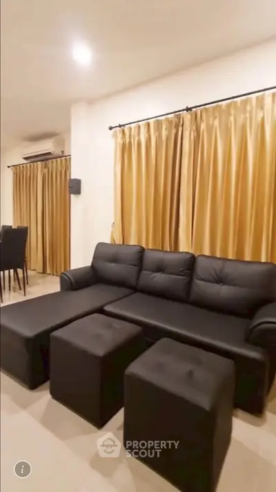 Spacious living room with elegant black sofa and golden curtains, perfect for modern living.