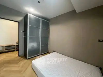 Modern minimalist bedroom with sleek wardrobe and wooden flooring.