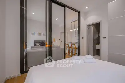 Modern bedroom with glass partition and view into stylish living area