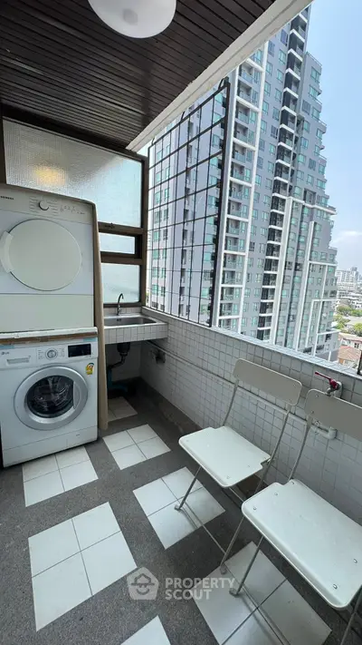 Modern balcony with washer, dryer, and city view in high-rise apartment