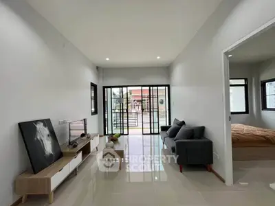 Modern living room with sleek furniture and large windows leading to a spacious balcony.