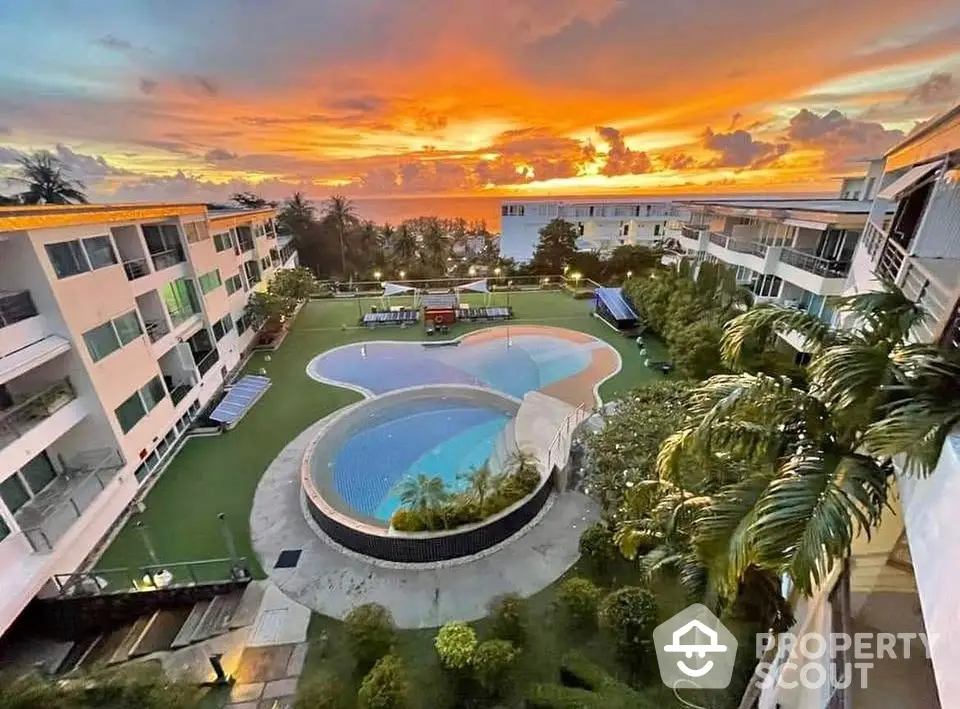 Stunning sunset view over modern apartment complex with pool and lush greenery.