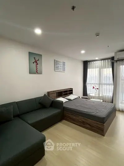 Modern studio apartment with cozy bed and stylish sofa in bright living space.